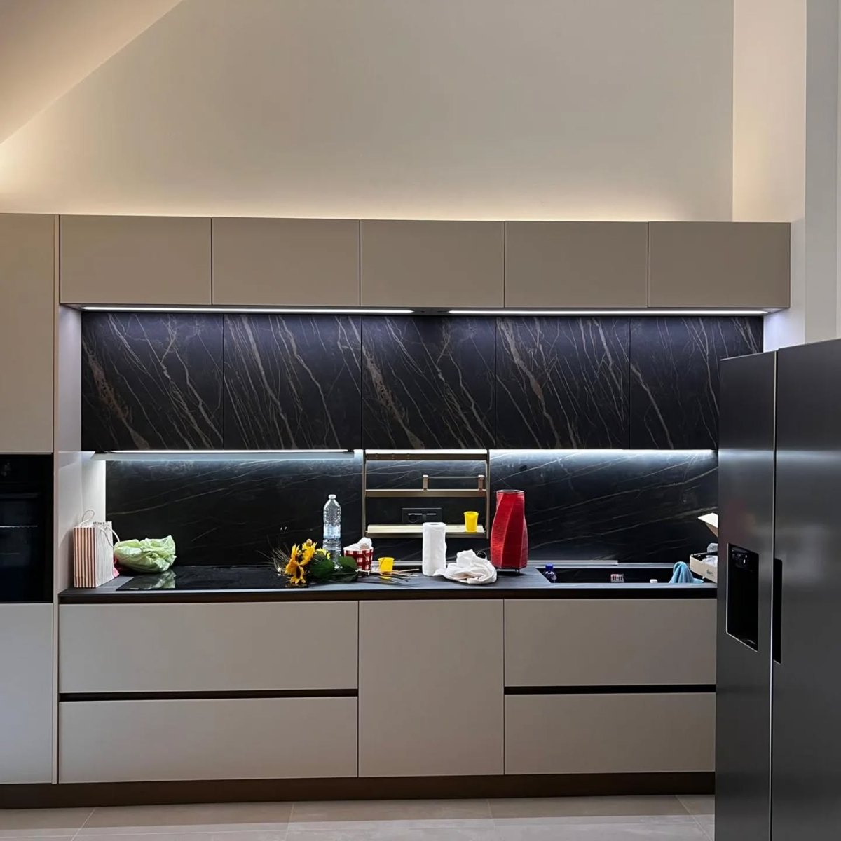 Cucina con ante color tortora e schienale in gres effetto marmo scuro in una casa vicino a Pinerolo